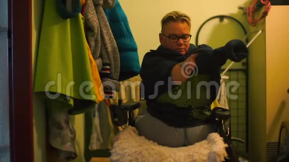 一个残疾人在公寓的走廊里脱下毛衣视频的预览图
