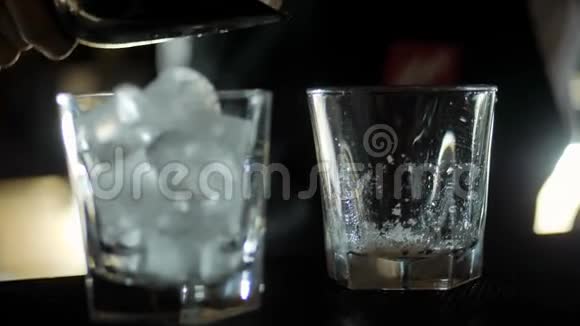 酒保在酒吧柜台上的空鸡尾酒杯中加入冰块视频的预览图