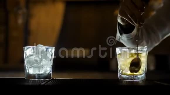 酒吧老板倒威士忌用水晶杯和冰块混合视频的预览图