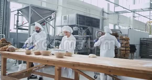 面包业快乐的工人在他们的餐桌上工作为烤面包做面团快乐视频的预览图