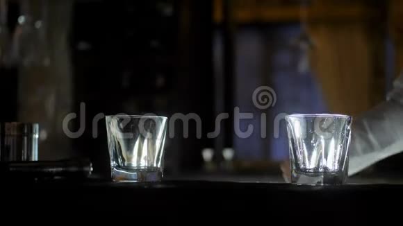 酒保在酒吧柜台上的空鸡尾酒杯中加入冰块视频的预览图