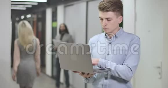 年轻的白人男子在笔记本电脑键盘上打字看着相机和微笑的肖像自信的上班族视频的预览图