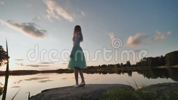 长头发的女孩在日落时在湖上旋转录像在移动视频的预览图