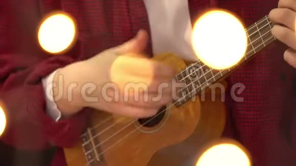 年轻的时髦女人弹着四弦琴吉他背景灯在前景中燃烧4克视频的预览图