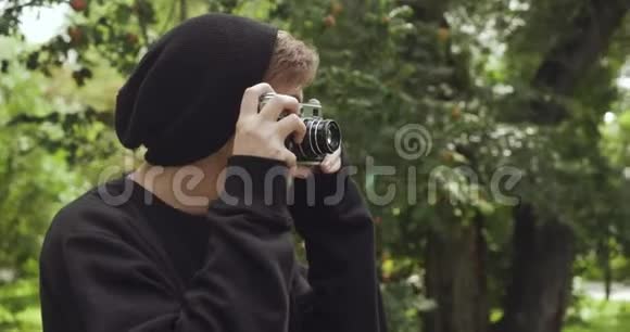 戴着黑色帽子的年轻潮人在老式相机上拍照视频的预览图