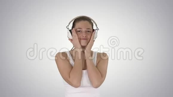 女人带着耳机听音乐在渐变背景上做滑稽的脸视频的预览图