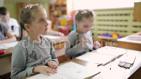 双胞胎女孩坐在学前班的书桌前学校里的孩子们坐在桌子旁视频的预览图