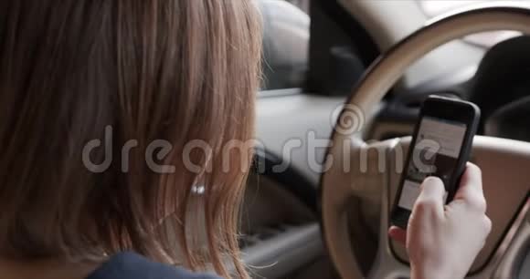 女人坐在汽车的车轮后面翻着社交网络的饲料视频的预览图