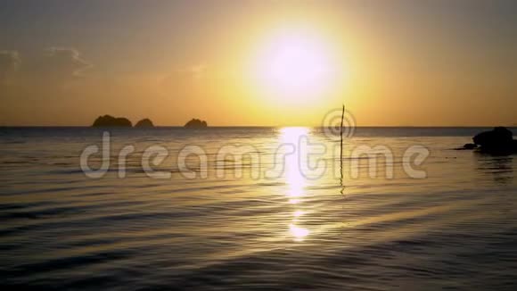 一艘木船在海岸附近的海浪上滑行背景中的大石头热带岛屿浪漫故事视频的预览图