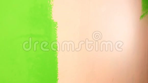 人手用油漆滚筒将粉红色的墙涂成鲜绿色特写镜头视频的预览图