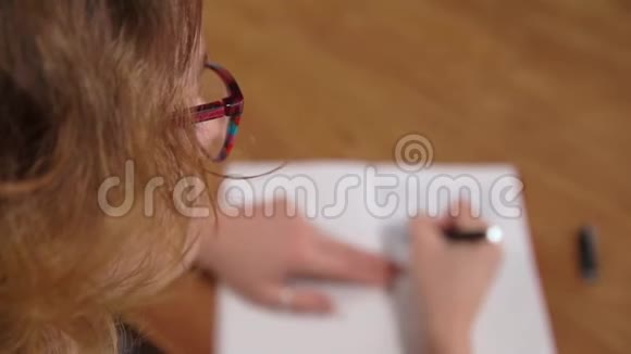 年轻女子用墨水笔在白色笔记本上写文字模糊视频的预览图