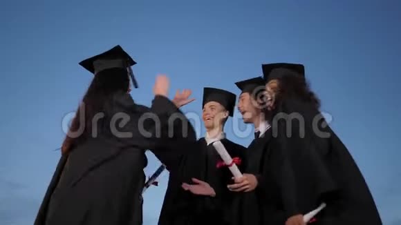 快乐毕业的学生多民族群体在毕业典礼后拥抱和做高五视频的预览图