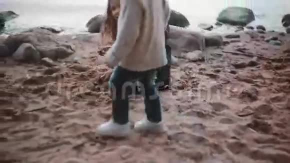 可爱的小女孩坐在岸上玩耍手里拿着沙子然后倒在地上哥哥去妹妹那里视频的预览图