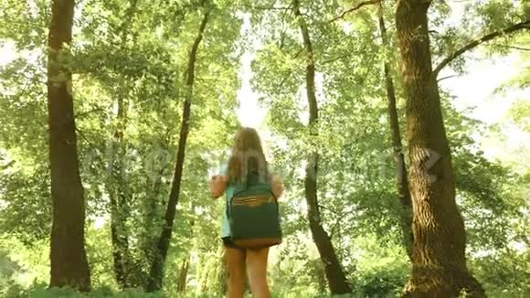 徒步旅行者留着长发在森林里散步自由女孩旅行者带着背包和视频的预览图