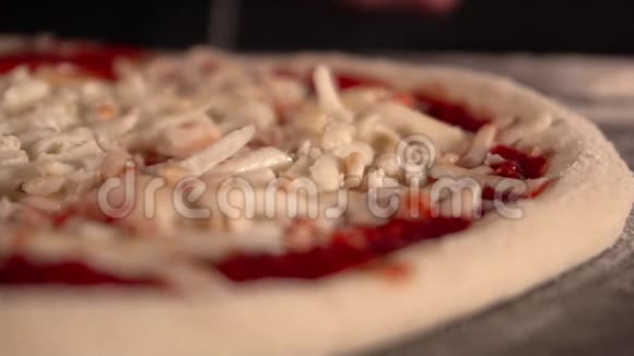 厨师的手在披萨上撒了几片意大利腊肠和奶酪专业人员准备意大利香肠披萨店视频的预览图