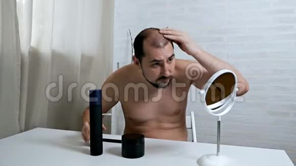 担心脱发镜子前一个秃顶的人照顾他的头发用一种方法来生长头发以防万一视频的预览图