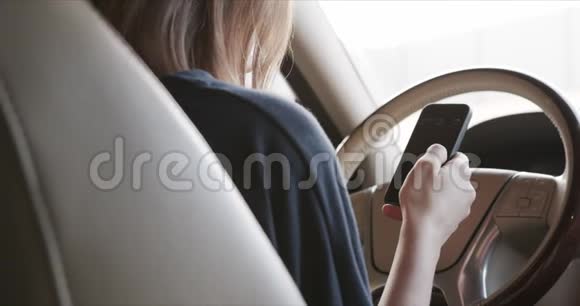 女人坐在汽车的车轮后面翻着社交网络的饲料视频的预览图