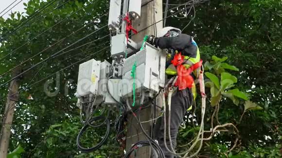 专业电工在电杆上进行安装工作专业设备电工在危险公司工作视频的预览图