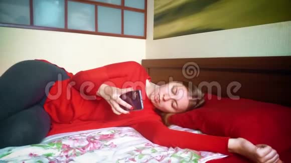 女孩在手机浏览器中翻页在床上休息的女孩视频的预览图