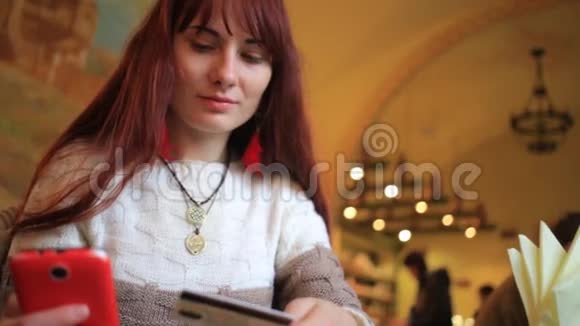 美丽的女子网上银行使用智能手机在线购物信用卡在咖啡馆的生活方式视频的预览图
