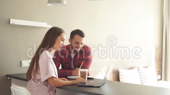 可爱的年轻夫妇在明亮的卧室里讨论日常工作使用笔记本电脑视频的预览图