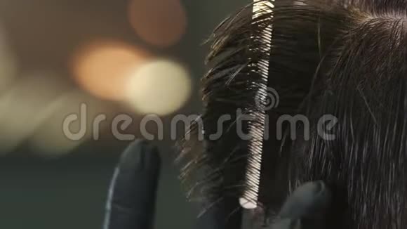 戴着黑色手套的理发师用把剪刀把病人的头发弄湿了视频的预览图