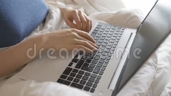 漂亮的女孩在床上用笔记本电脑在社交网络中交流在家工作视频的预览图