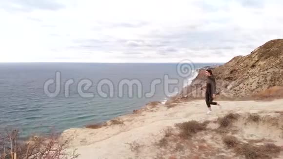 鸟瞰一个年轻的女人感觉自由站在悬崖边上的海洋户外运动的女运动员视频的预览图