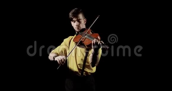 男子小提琴演奏家在黑色背景下在黑暗正面的视野视频的预览图