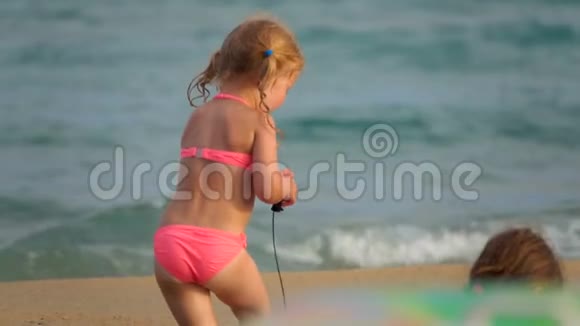 快乐的女孩在沙滩上拖着玩具视频的预览图