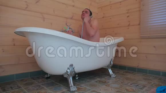 一个男人在淋浴下坐在浴室里刷牙视频的预览图