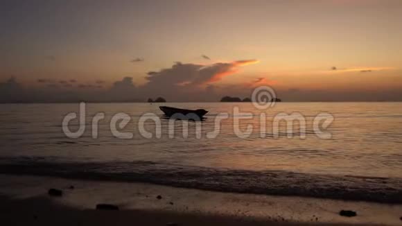 一艘木船在海岸附近的海浪上滑行背景中的大石头热带岛屿浪漫故事视频的预览图