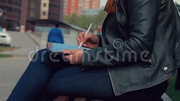 女人在平板电脑上画画公园里的女孩坐在长凳上画着一块图形平板视频的预览图
