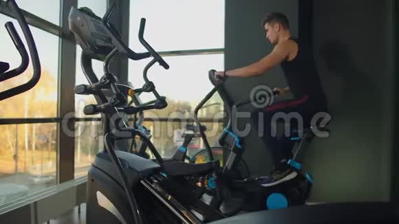在健身房里使用空中自行车来适应年轻人强壮的男性运动员在健康俱乐部做循环有氧运动视频的预览图