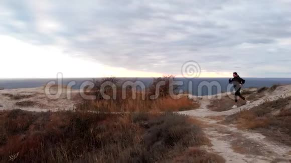 在山上慢跑运动的鸟瞰图女性的剪影映衬着夕阳的阴云天空视频的预览图