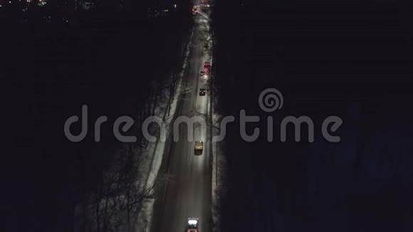 从无人驾驶飞机上看到汽车在夜间穿过森林的冬季道路上行驶视频的预览图