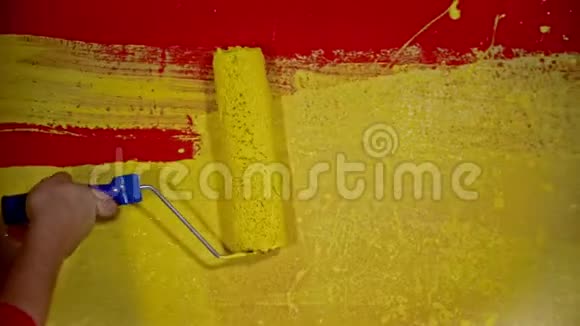 一个公寓维修工一个人用滚筒把一面红色的墙涂成黄色的油漆视频的预览图