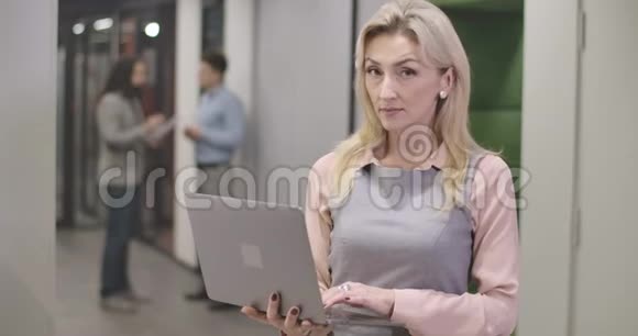 漂亮的白种人年轻女人站在开放空间办公室里看着相机微笑着成功视频的预览图