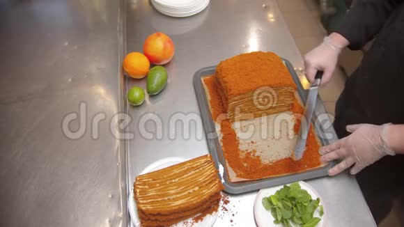 厨师用锋利的刀切出一大块蜂蜜蛋糕桌子上的水果视频的预览图