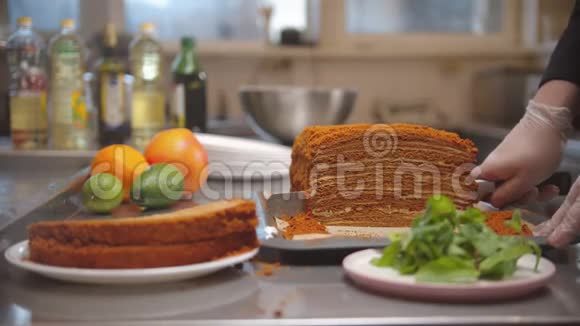 厨师用锋利的刀切出一大块蜂蜜蛋糕然后把它放在盘子里视频的预览图