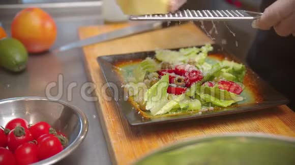 厨师在装饰好的盘子上放沙拉在上面撒上奶酪视频的预览图
