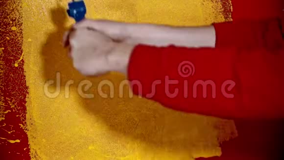 一个人用滚筒在红色的墙上涂上黄色的油漆视频的预览图