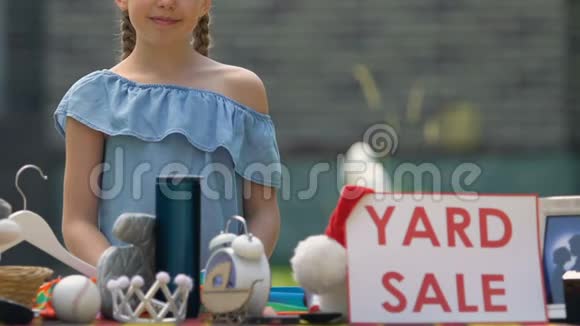 微笑的女孩在桌子上摆卖招牌孩子在卖不用的东西邻居视频的预览图