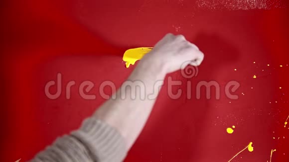 一个人在红墙上用黄色油漆粉刷房子视频的预览图