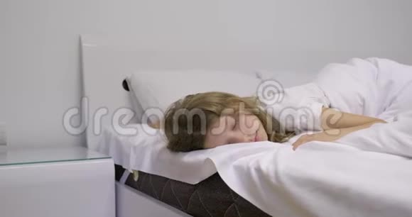 睡在白床上的女孩醒来用手摸睡眼孩子想睡觉视频的预览图