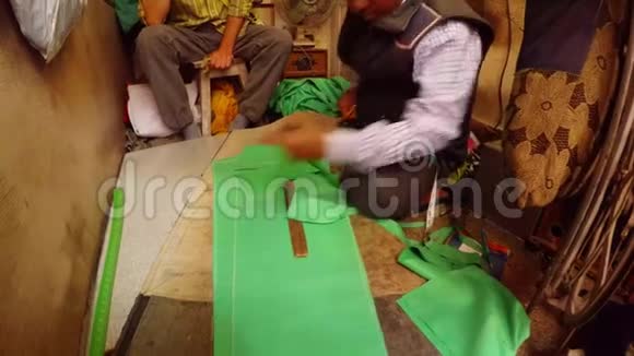 印度裁缝把绿色布缝纫车间的裤子图案拼在一起视频的预览图