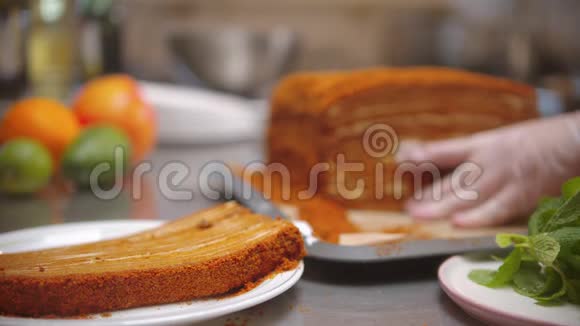 厨师把一大块蜂蜜蛋糕切出来放在独立的盘子里视频的预览图