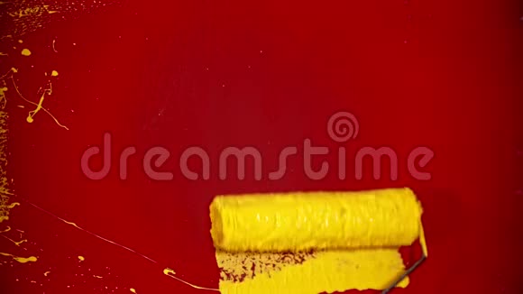 一个人用滚筒重新涂上黄色油漆的红墙视频的预览图