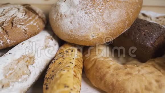 木桌上不同种类的新鲜面包棕色背景面包的独立品种视频的预览图