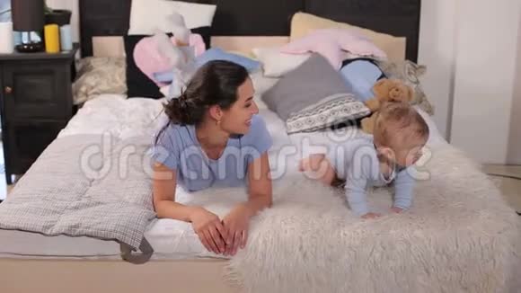 妈妈带着一个小孩子躺在床上躺在卧室里的毛茸茸的毯子上视频的预览图